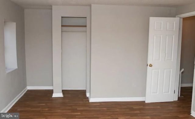 unfurnished bedroom featuring a closet and dark hardwood / wood-style flooring