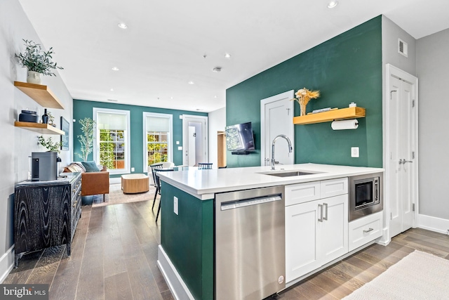 kitchen featuring appliances with stainless steel finishes, hardwood / wood-style flooring, white cabinetry, a kitchen island with sink, and sink