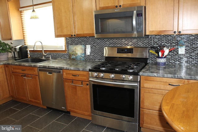 kitchen featuring pendant lighting, appliances with stainless steel finishes, dark tile patterned floors, decorative backsplash, and sink