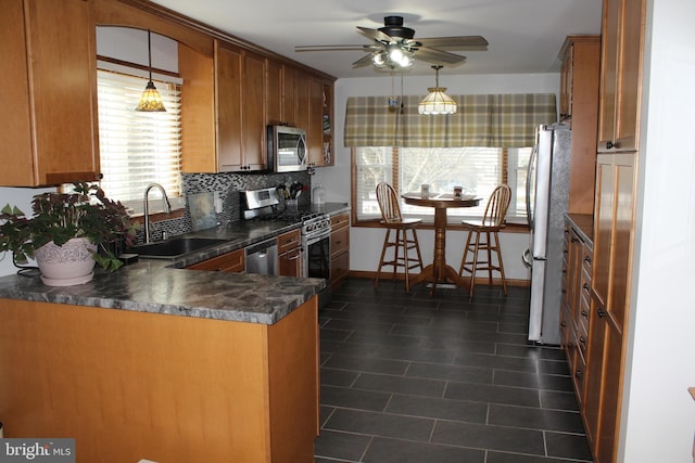 kitchen with stainless steel appliances, tasteful backsplash, sink, kitchen peninsula, and ceiling fan