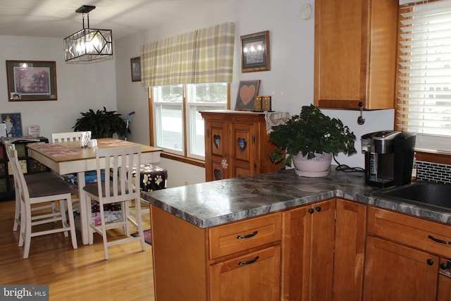 kitchen with sink, light hardwood / wood-style floors, and decorative light fixtures