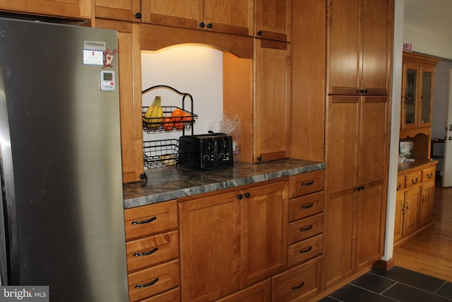 kitchen with dark tile patterned floors and stainless steel refrigerator