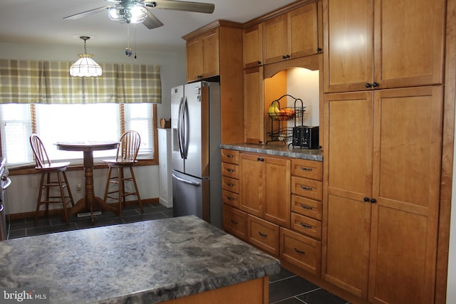 kitchen with stainless steel refrigerator with ice dispenser, dark tile patterned flooring, ceiling fan, and hanging light fixtures