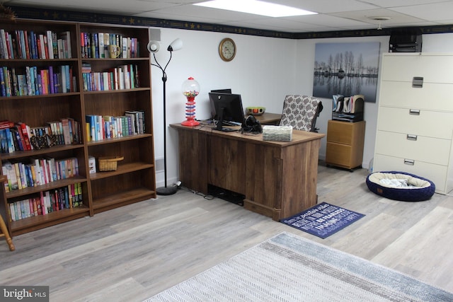 office with light wood-type flooring and a drop ceiling