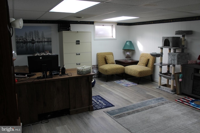 living room featuring wood-type flooring and a paneled ceiling