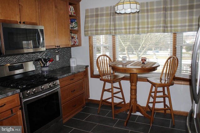 kitchen with backsplash, stainless steel appliances, and dark stone counters