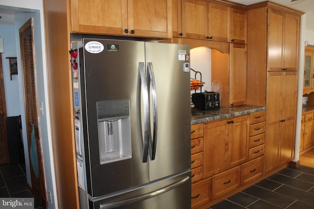 kitchen featuring stainless steel fridge with ice dispenser and dark tile patterned flooring