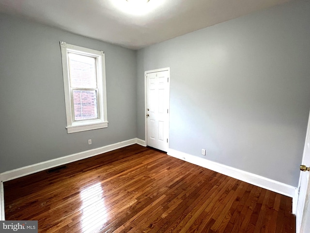 unfurnished room with dark hardwood / wood-style flooring