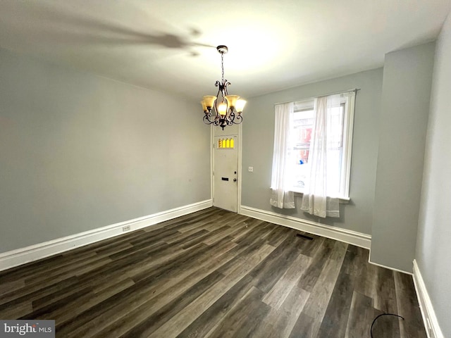 empty room featuring dark wood-type flooring and a notable chandelier