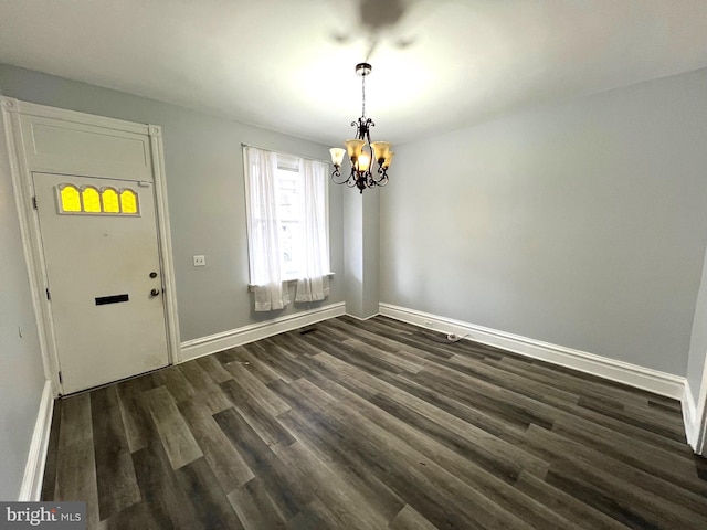 unfurnished dining area with dark wood-type flooring and an inviting chandelier