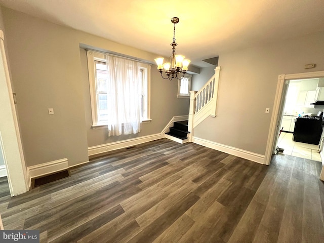 unfurnished dining area featuring dark hardwood / wood-style flooring and a notable chandelier