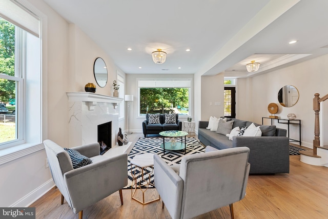 living room featuring light hardwood / wood-style flooring, a high end fireplace, and plenty of natural light