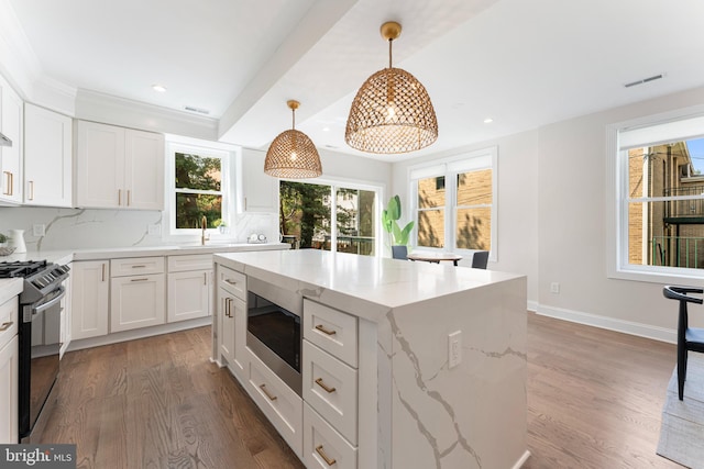 kitchen featuring built in microwave, decorative light fixtures, gas stove, and white cabinets