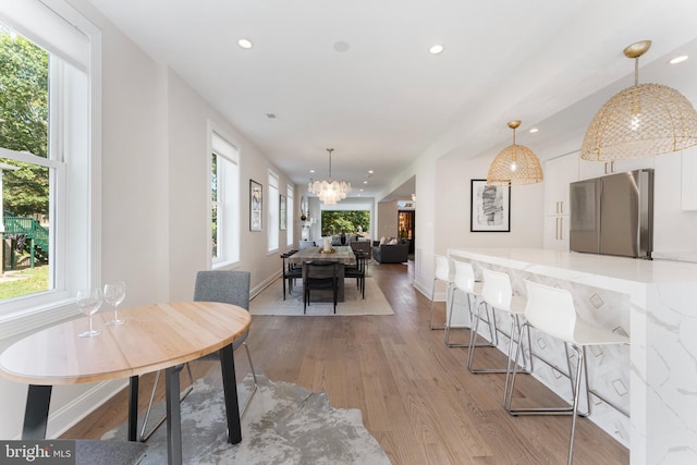 dining area featuring a notable chandelier, light hardwood / wood-style flooring, and plenty of natural light