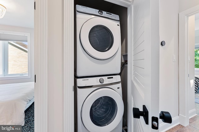 clothes washing area with stacked washer and dryer and hardwood / wood-style floors