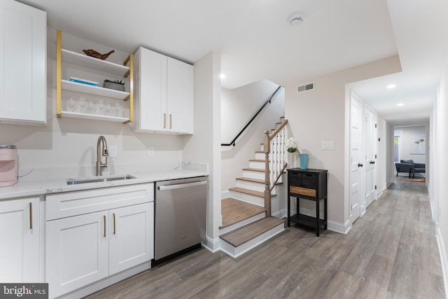 kitchen featuring sink, dishwasher, white cabinetry, light hardwood / wood-style floors, and light stone countertops