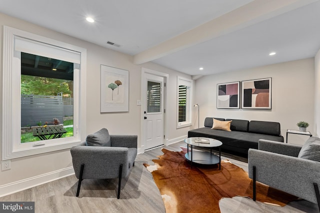 living room with light hardwood / wood-style floors and beamed ceiling