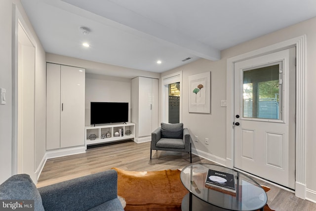 living room with beamed ceiling and light hardwood / wood-style flooring