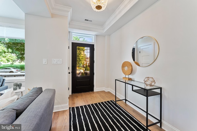 foyer featuring crown molding, a chandelier, and light wood-type flooring