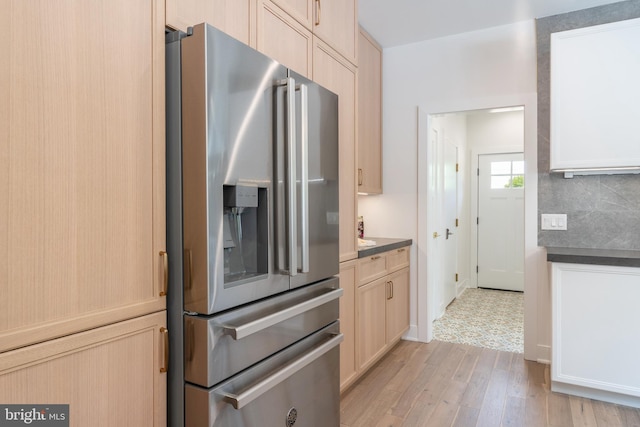 kitchen with light brown cabinets, stainless steel fridge with ice dispenser, and light hardwood / wood-style flooring