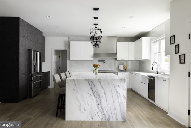 kitchen with a center island, a kitchen bar, white cabinetry, light hardwood / wood-style flooring, and hanging light fixtures