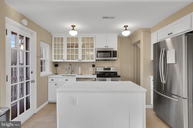 kitchen featuring sink, tasteful backsplash, white cabinetry, a center island, and stainless steel appliances