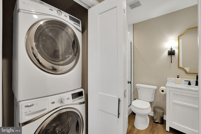 laundry area featuring wood-type flooring and stacked washer / drying machine