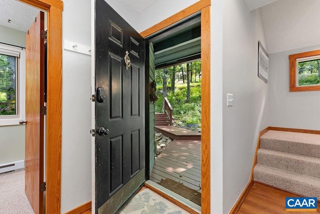 foyer entrance with light wood-type flooring, a baseboard heating unit, and plenty of natural light