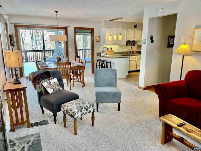 living room featuring light colored carpet, sink, and a textured ceiling