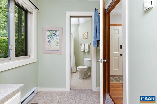 bathroom with toilet, baseboard heating, and tile patterned floors