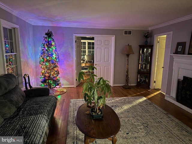 living room featuring a tiled fireplace, dark hardwood / wood-style flooring, and crown molding