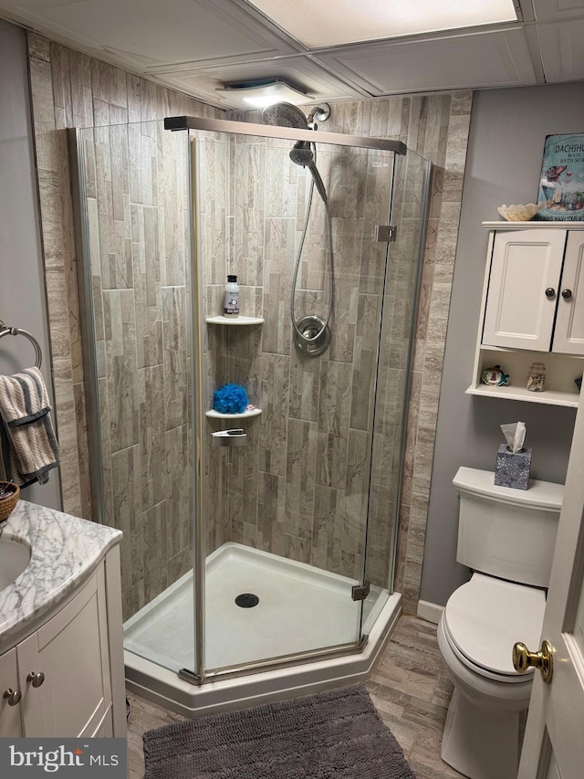 bathroom with hardwood / wood-style flooring, an enclosed shower, vanity, and toilet