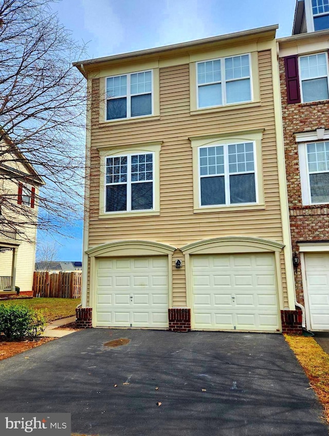 multi unit property featuring aphalt driveway, an attached garage, and fence