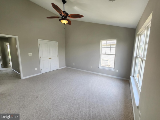 unfurnished bedroom featuring carpet, baseboards, a closet, and high vaulted ceiling