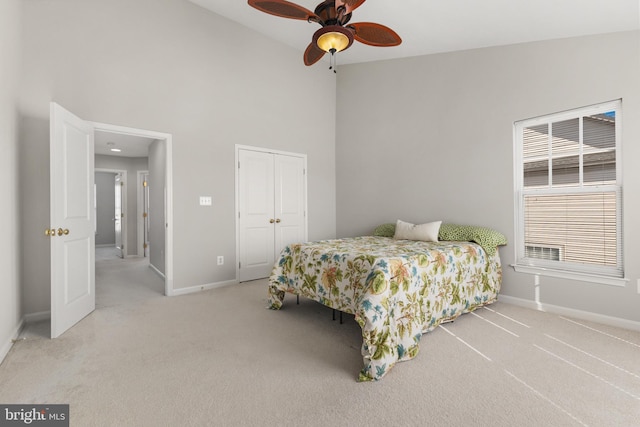 carpeted bedroom with ceiling fan, baseboards, a closet, and high vaulted ceiling