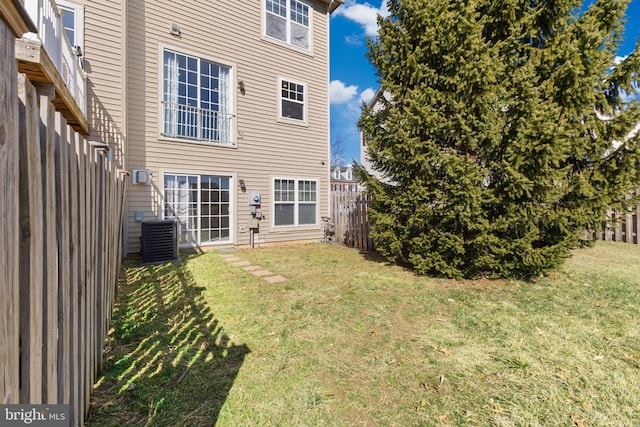 rear view of property with a lawn, a fenced backyard, and central AC