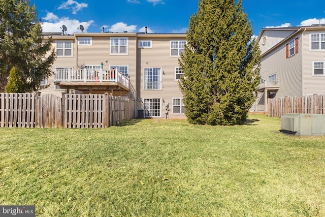 rear view of property with central air condition unit, a lawn, and a fenced backyard