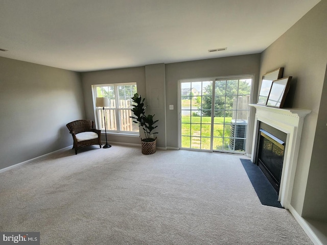 unfurnished room with carpet floors, a fireplace with flush hearth, visible vents, and baseboards