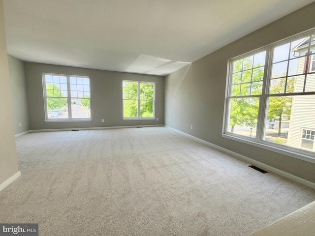 carpeted spare room featuring visible vents and baseboards