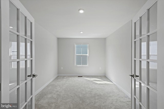 unfurnished room with light carpet and french doors