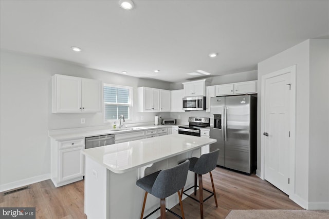 kitchen with appliances with stainless steel finishes, sink, white cabinets, and a center island