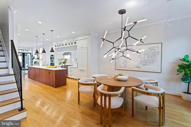 dining room with a notable chandelier, crown molding, and light hardwood / wood-style floors