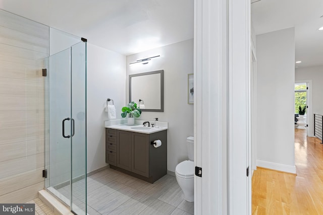 bathroom featuring wood-type flooring, toilet, an enclosed shower, and vanity