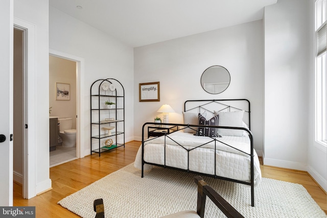 bedroom with multiple windows, wood-type flooring, and ensuite bathroom