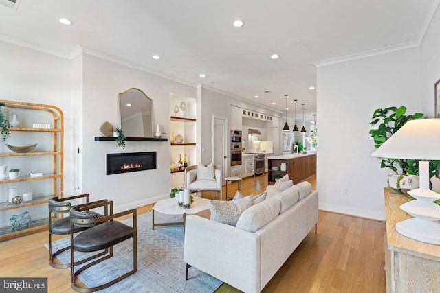 living room featuring sink, ornamental molding, and light wood-type flooring