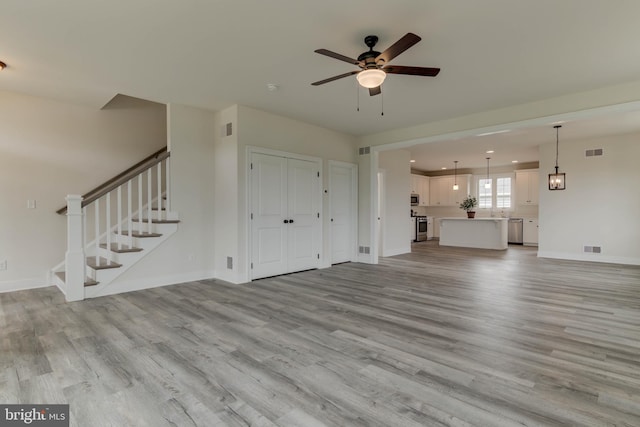 unfurnished living room featuring ceiling fan and light hardwood / wood-style flooring