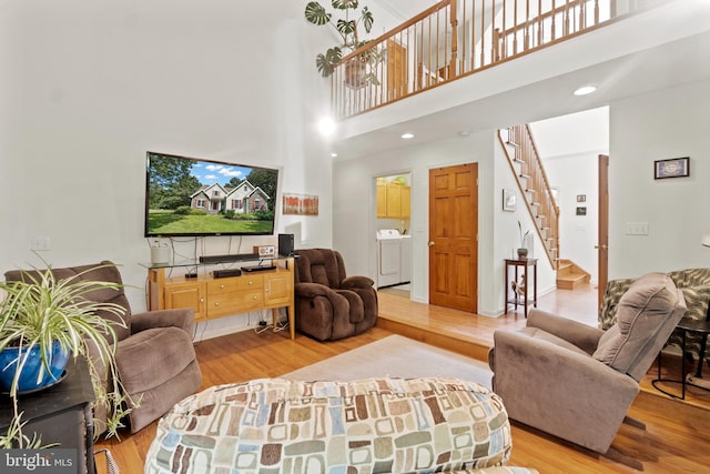 living room featuring light hardwood / wood-style floors, a high ceiling, and separate washer and dryer