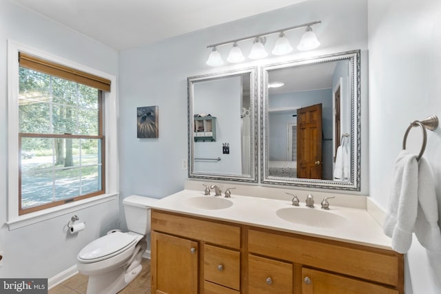 bathroom featuring toilet, a healthy amount of sunlight, tile patterned floors, and vanity