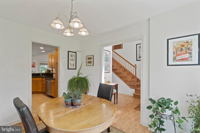 dining space with an inviting chandelier, light hardwood / wood-style flooring, and sink