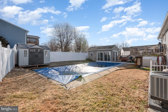 view of pool featuring a storage shed, a yard, central AC, a patio, and a wooden deck